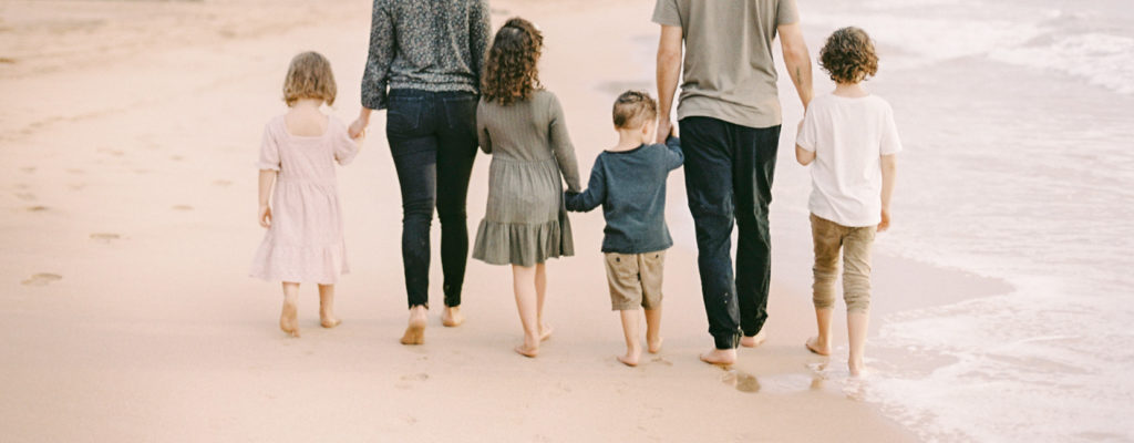 Large family walking on Maui beach without shoes