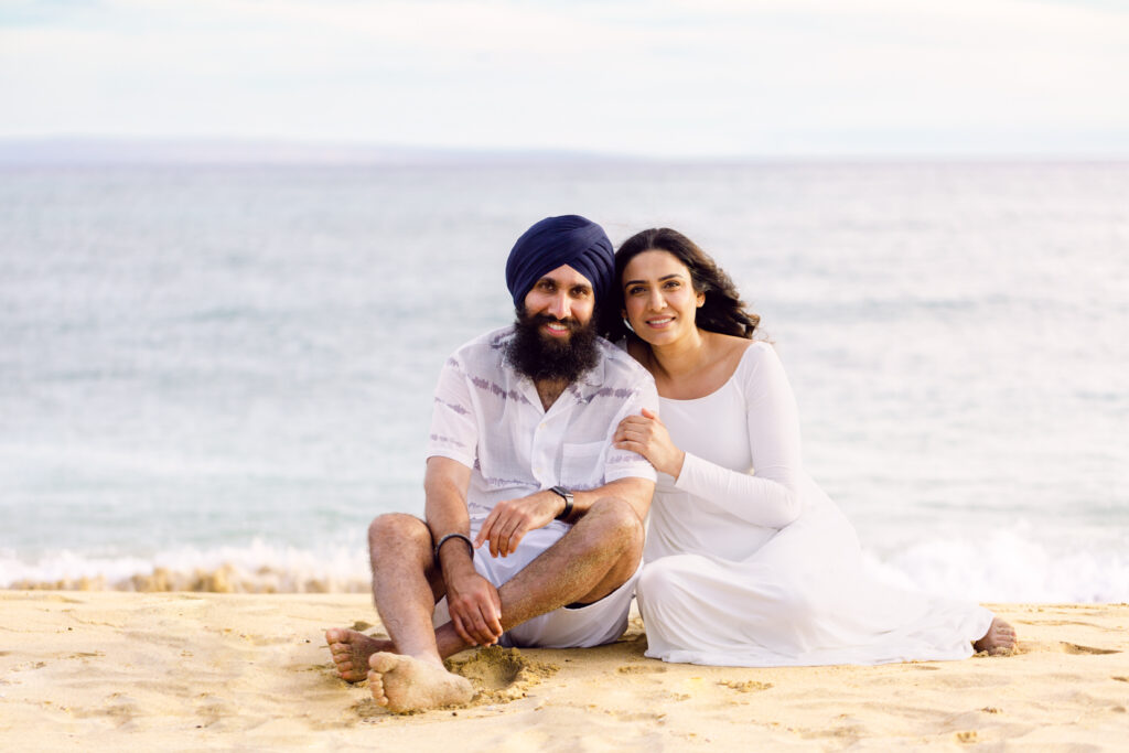 Couple sitting on sand posing for Maui beach babymoon photography session
