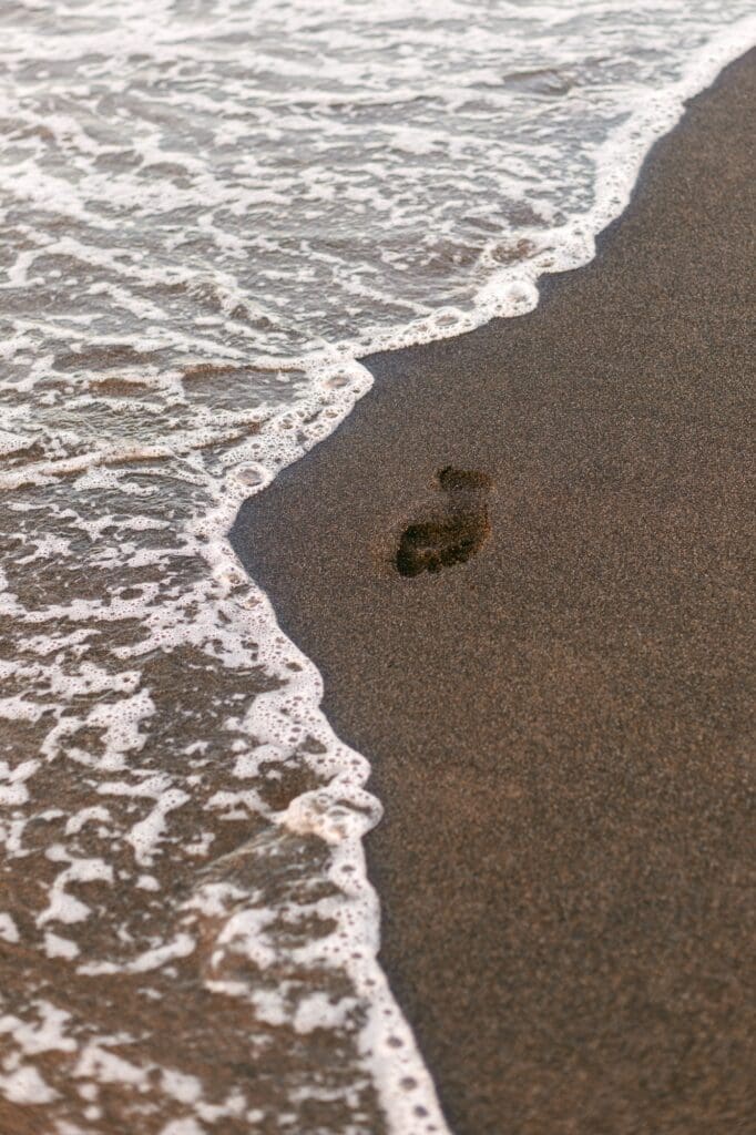 footprint in black sand on Maui
