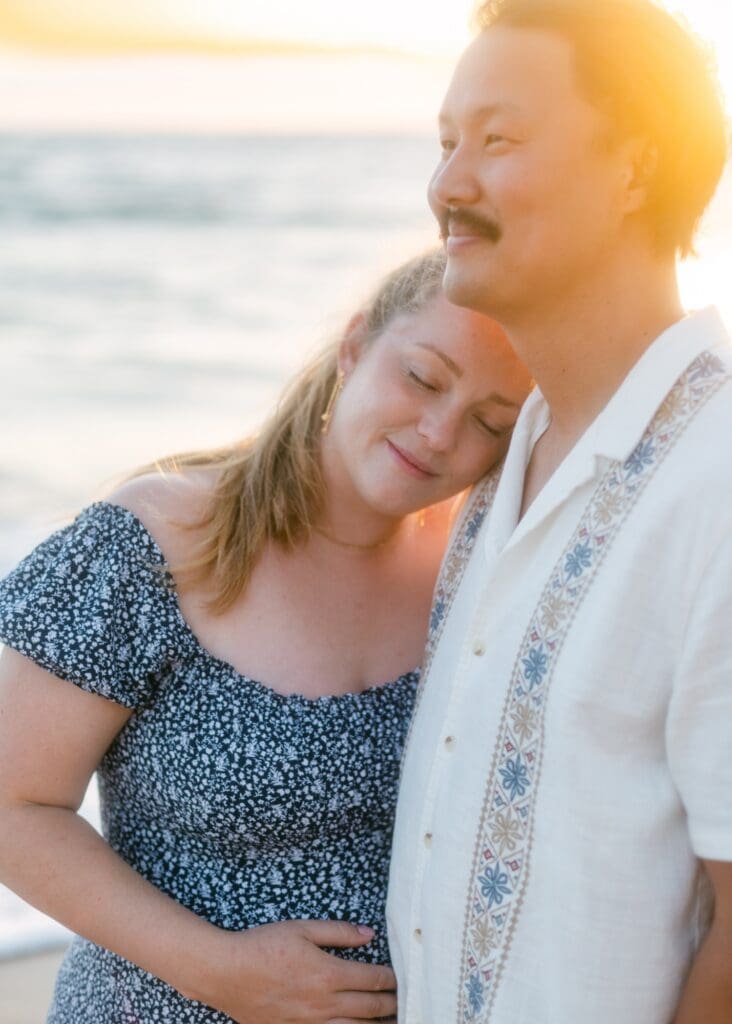 A quiet moment between a babymoon couple on the shore of Mokapu Beach during a South Maui sunset maternity photos
