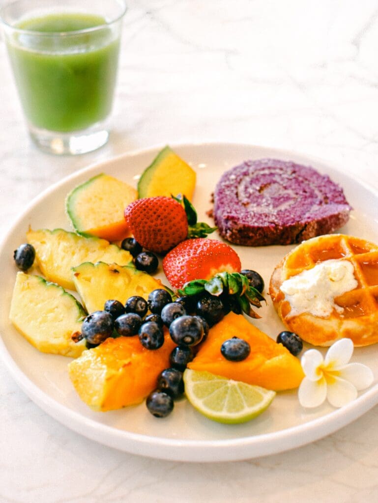 Plate of fresh fruit, mochi waffles, and ube roll cake from the breakfast buffet at Kaʻana Kitchen at the Andaz Maui in Wailea