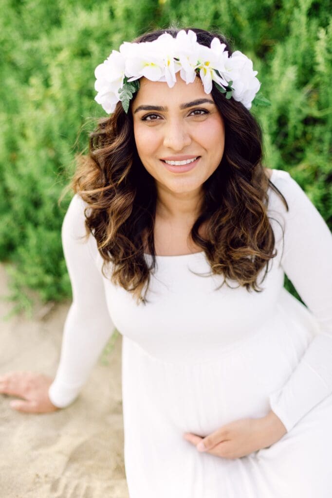 babymoon couple wearing white and Hawaiian lei during Maui maternity photos