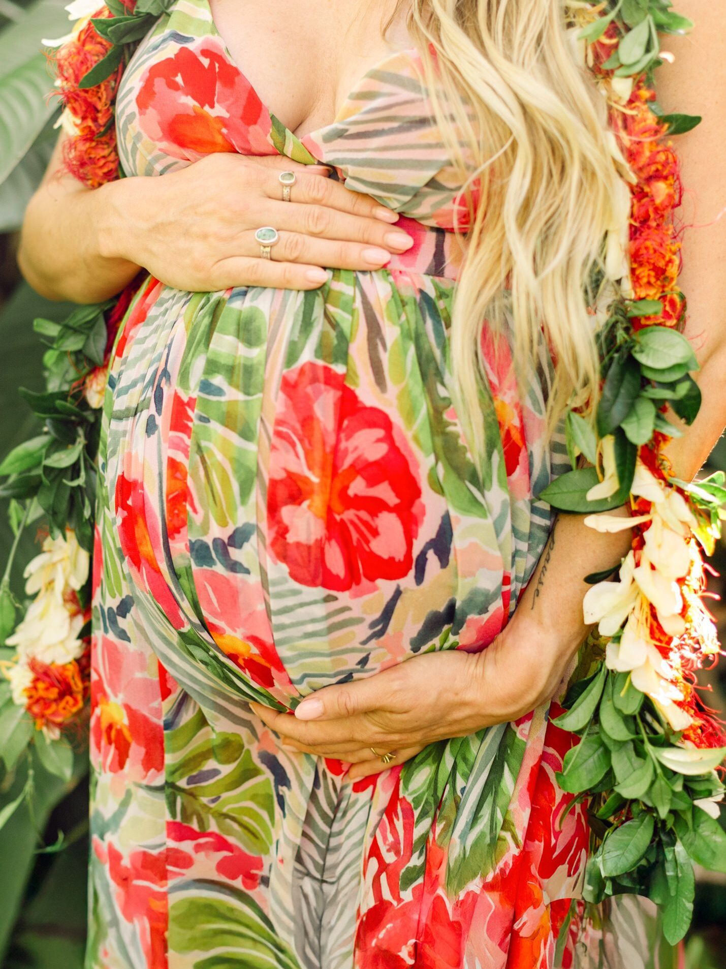 Close-up of a pregnant belly adorned with maile and ginger lei during a jungle babymoon session on Maui