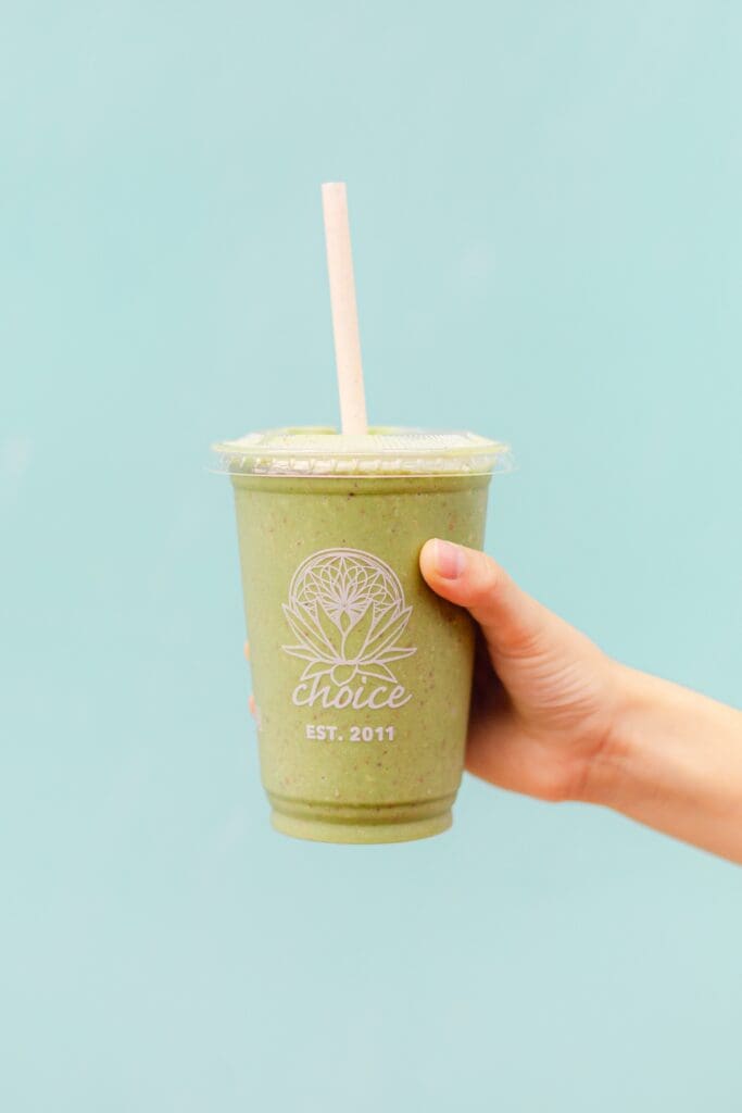 Holding a cup of Choice Health bar mint chip smoothie in Paia 