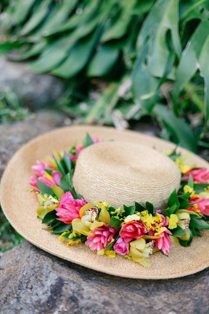 Close-up of a wide-brimmed sun hat adorned with a custom tropical flower crown (lei po’o) for a Maui maternity session.