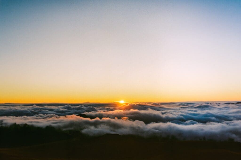 Stunning sunset maternity session at the Haleakalā summit above the clouds, showcasing unique volcanic Maui maternity photo locations