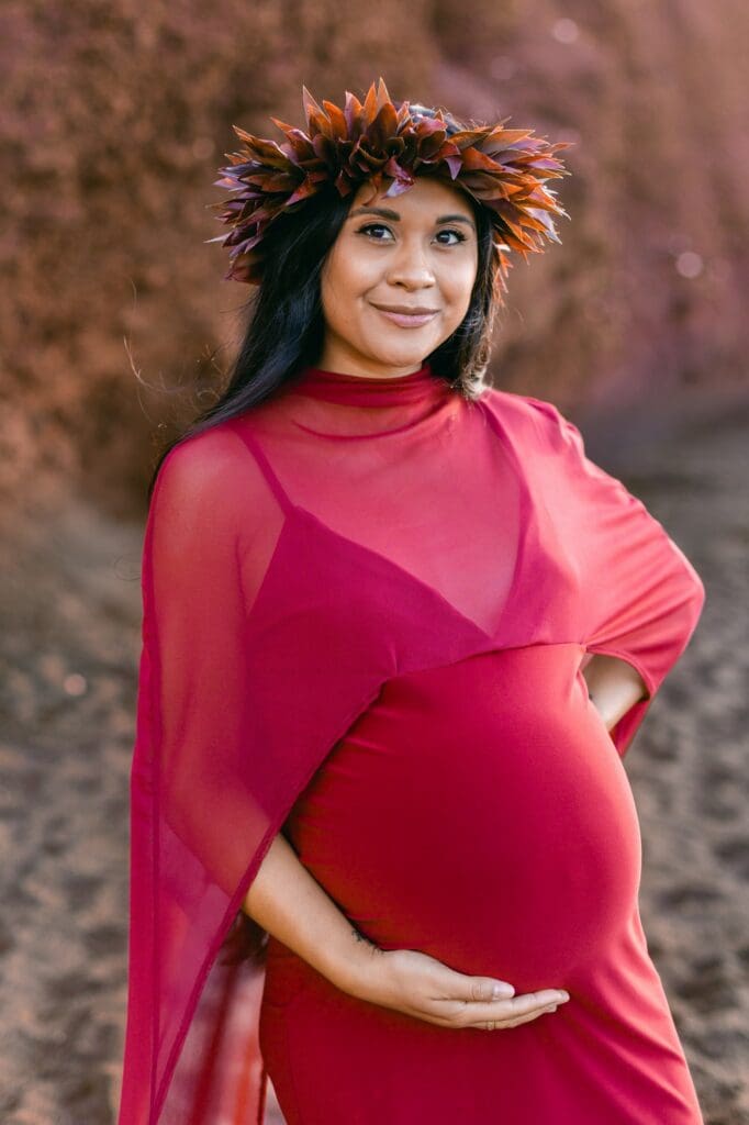 Pregnant woman in burgundy dress black sand beach Maui maternity photos