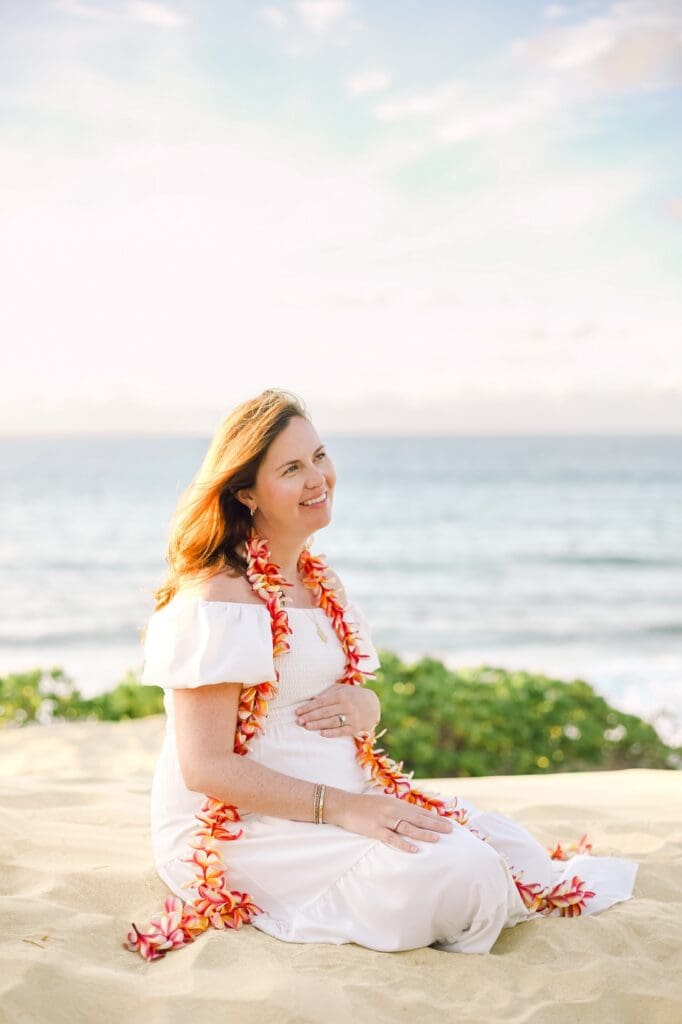 A woman in a flowing dress and a plumeria hapai lei overlooking the rugged West Maui coastline from the dunes at Ironwoods