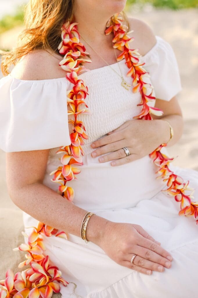 Soft sunset light catching the textures of the sand dunes and the delicate plumeria of a maternity lei