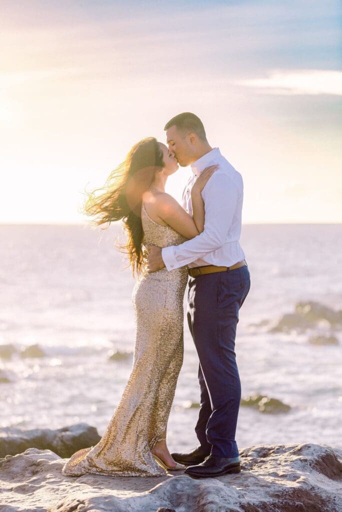 couple kissing at sunset on cliffs above Ironwoods Beach in Maui during babymoon