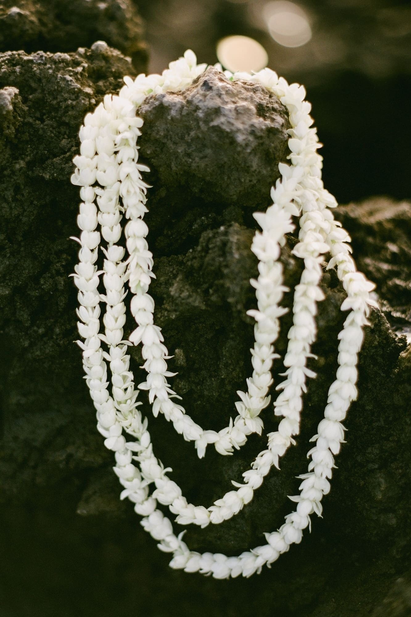 Maui maternity photos detail shot of tropical lei on black lava rock