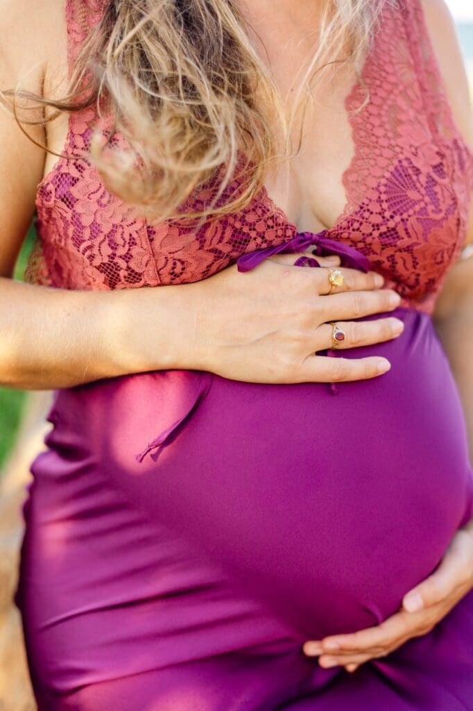 close-up maternity photo of baby bump in flowing silk dress on Maui red sand beach