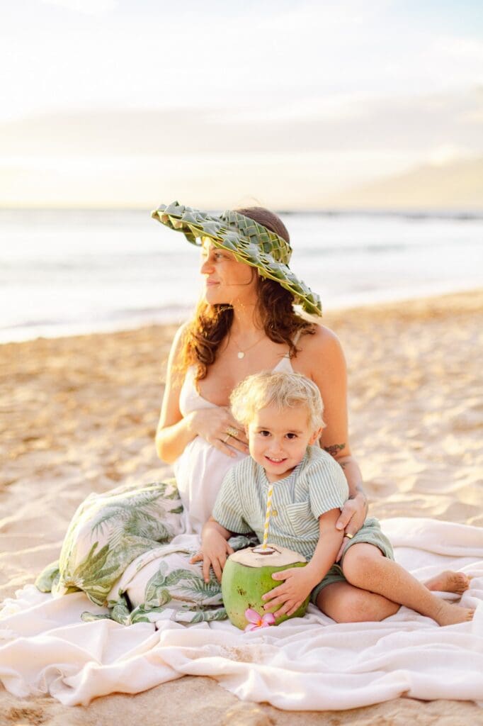 mother and toddler on picnic blanket enjoying sunset at Mākena Beach Maui during maternity photo session