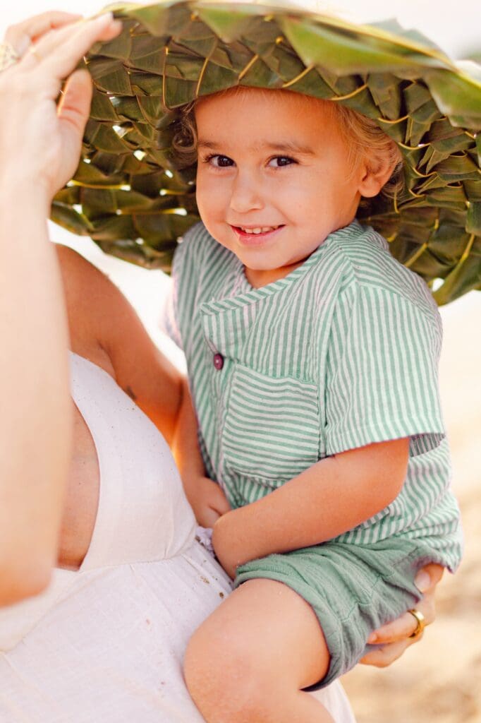 family enjoying sunset beach picnic with coconuts on white blanket at Mākena Beach Maui during maternity session