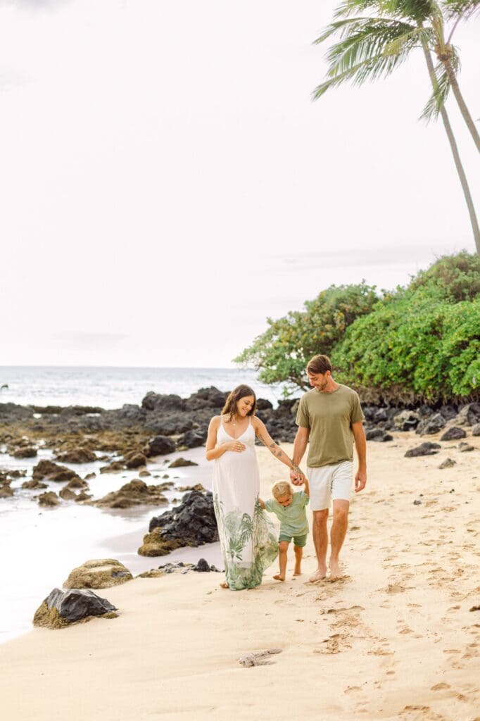 family walking hand in hand along Mākena Beach Maui during maternity photo session