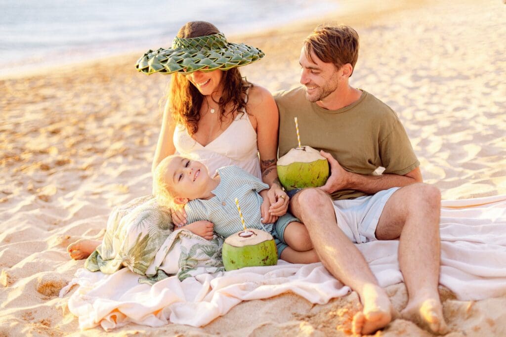 family laughing on picnic blanket at Makena Beach Maui during maternity photo session
